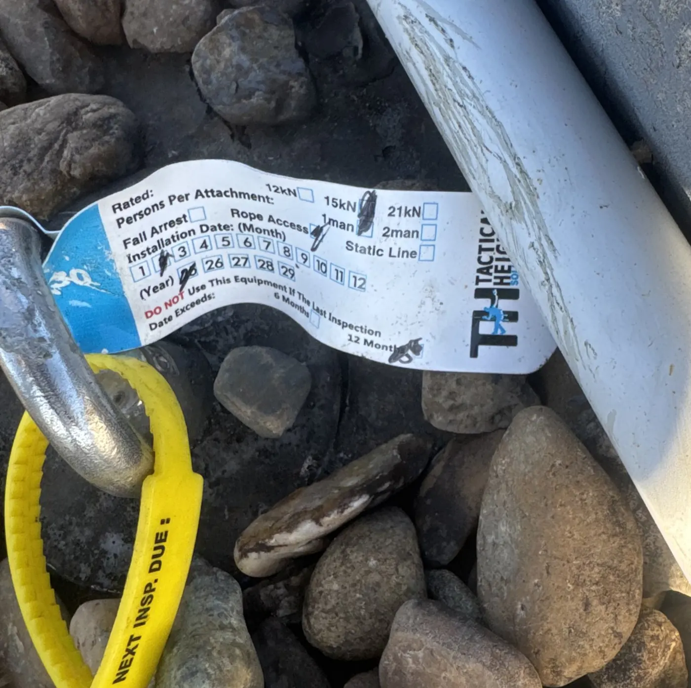 Tactical Height Solutions inspection tag fitted to a roof anchor, with the next inspection date