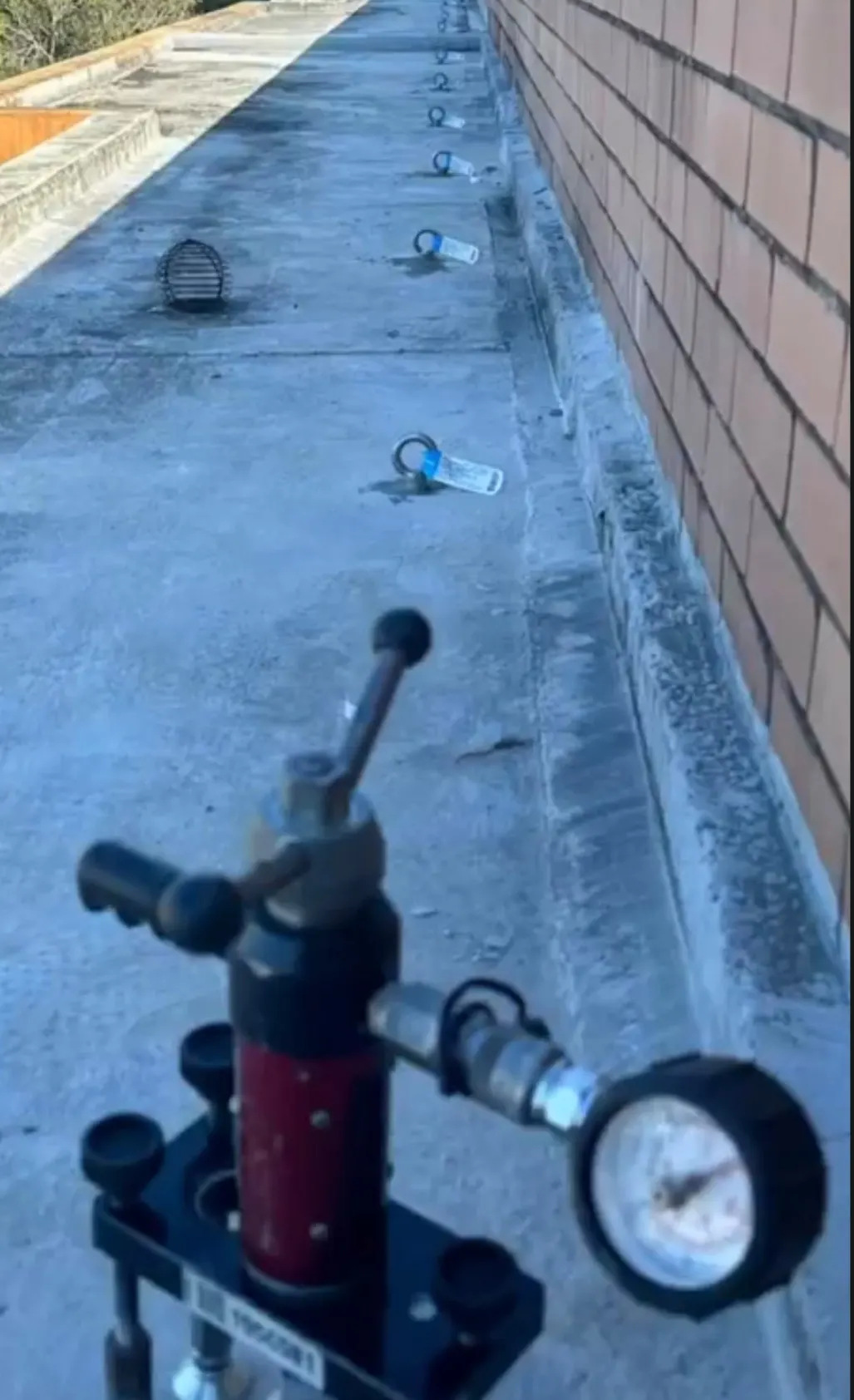 Anchor point load testing: tester set up beside a row of newly tagged roof anchors