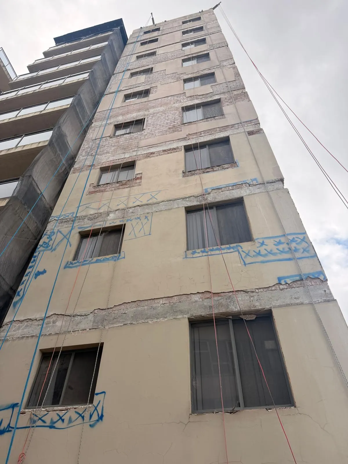 Concrete cracks and spalling marked in blue survey paint during a façade inspection on a Bankstown high-rise