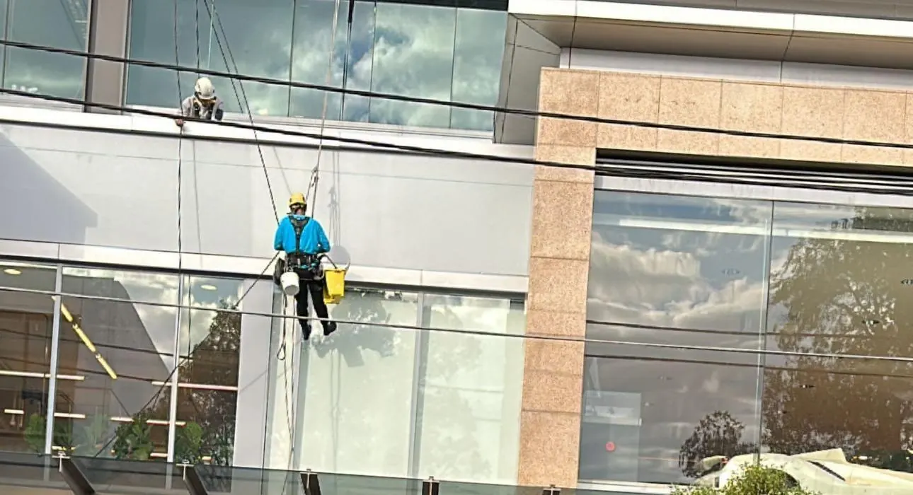 Commercial painting on rope: painter working on the façade of a showroom