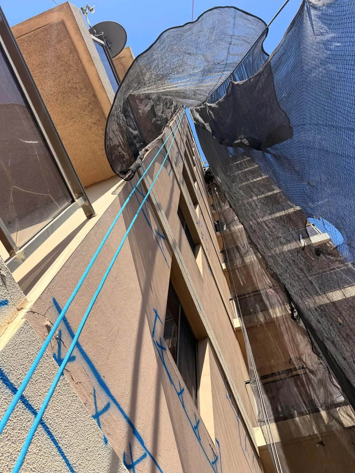 Containment netting rigged below rope access concrete repairs, seen from the base of the building