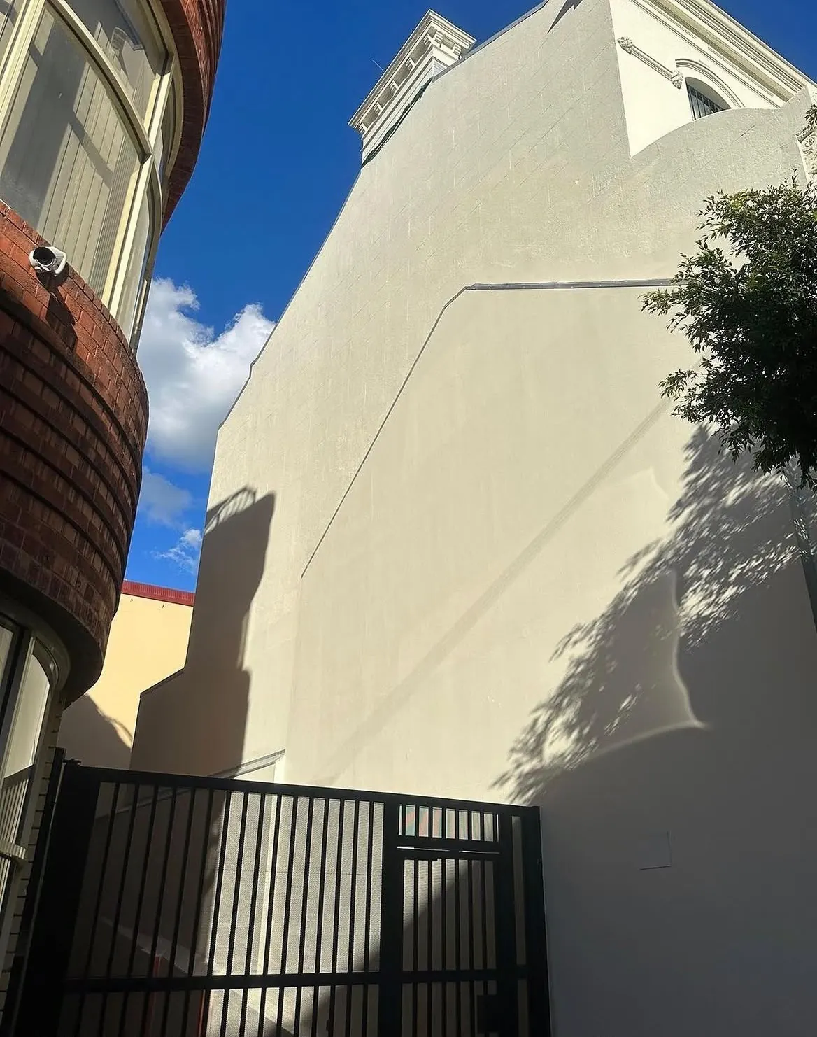 The rendered wall finished after the crack repairs and recoating, seen from the gate