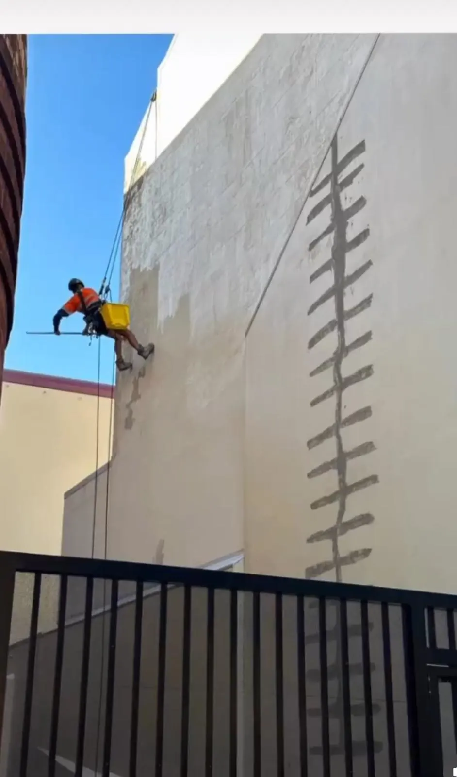 Building washing: technician cleaning a rendered wall from the rope