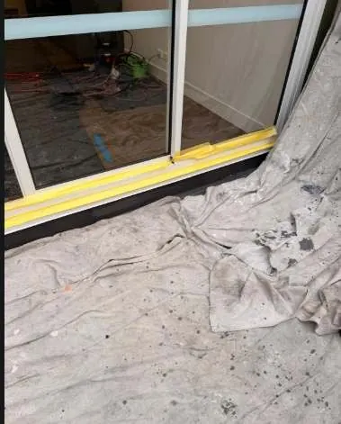 Drop sheets and taped plastic protecting a balcony and sliding door before façade repairs in Mascot