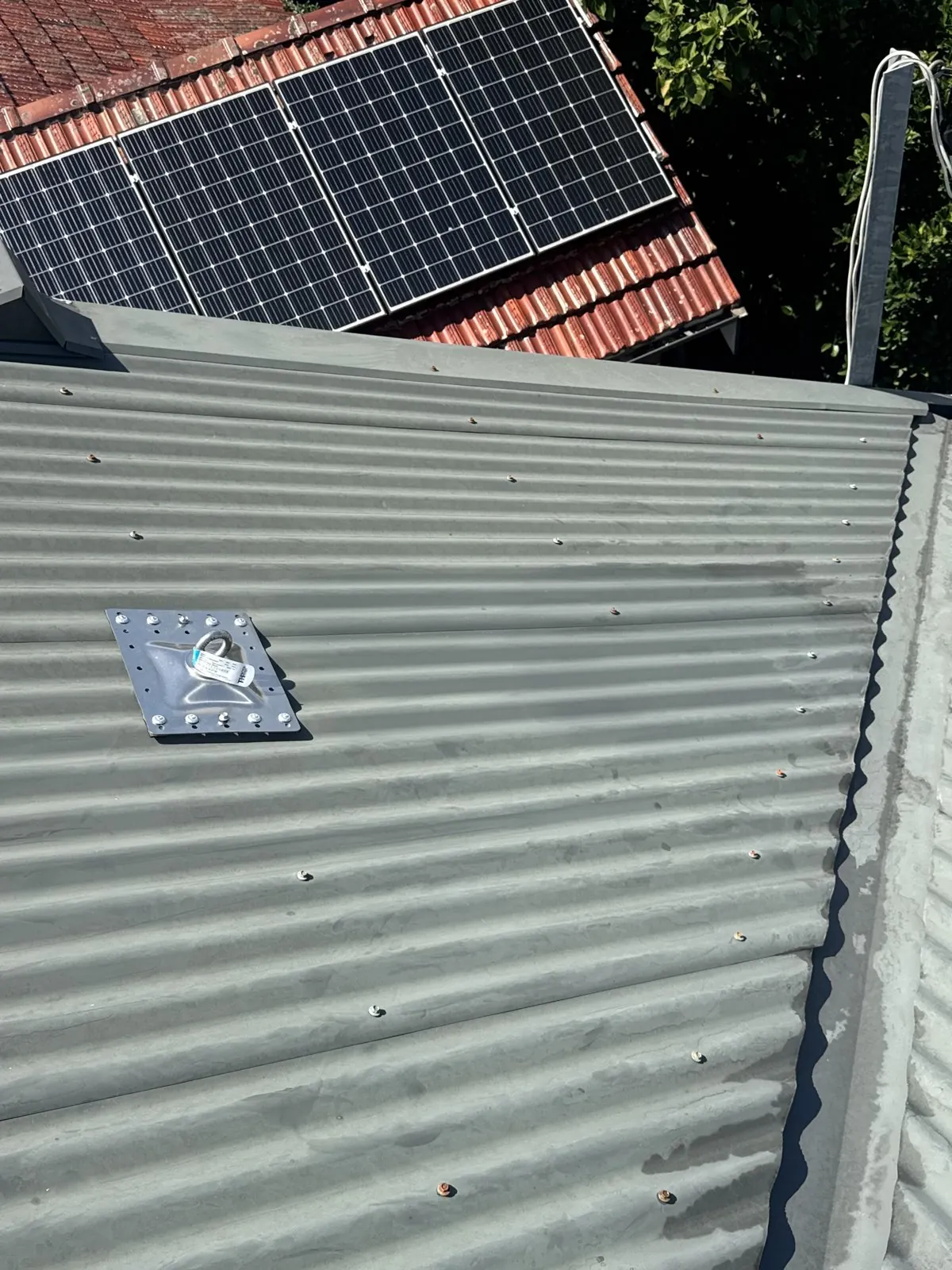Roof access anchor point installed on a corrugated metal roof