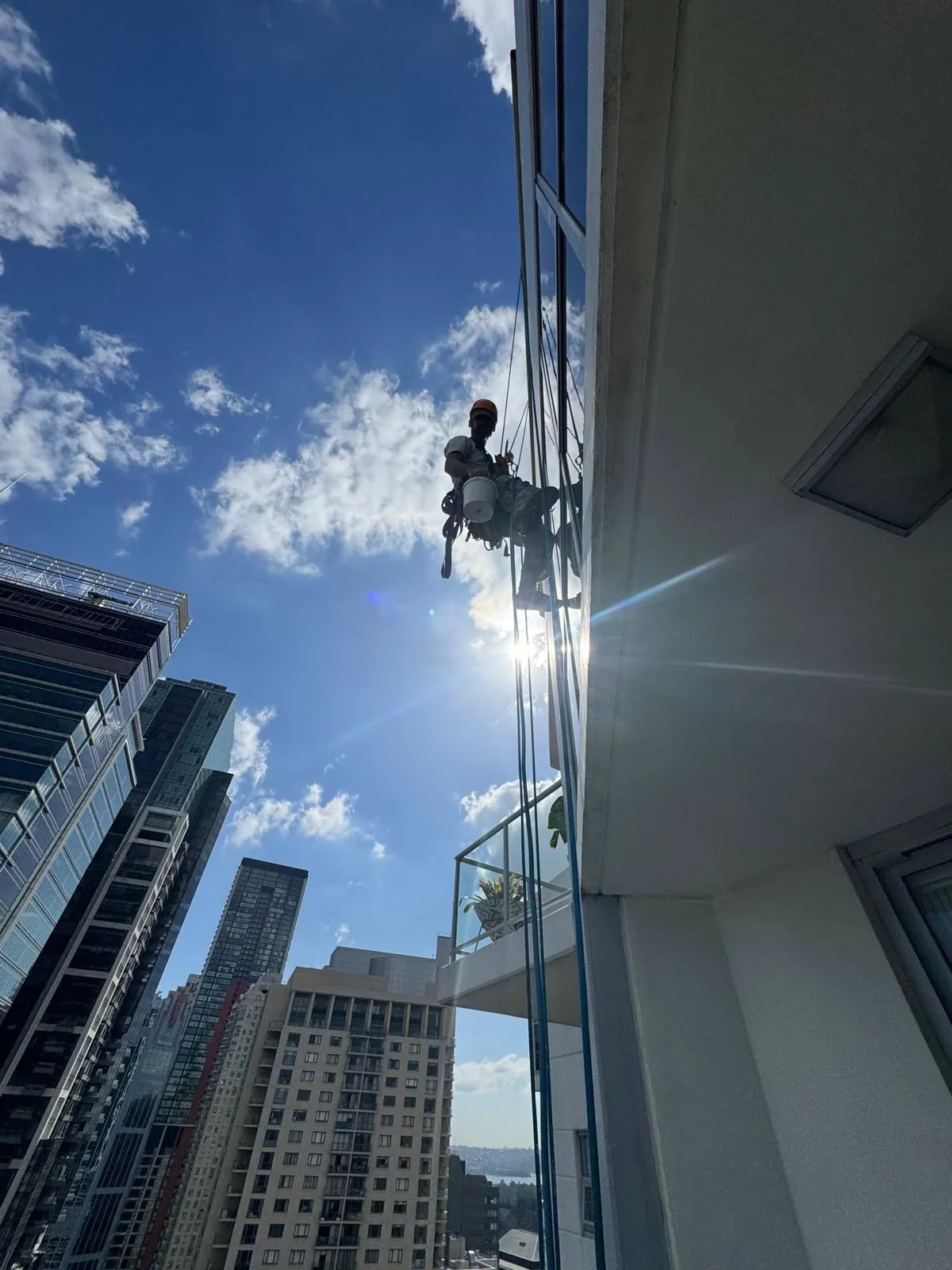 High-rise window cleaning: rope access technician with a bucket on a glass façade