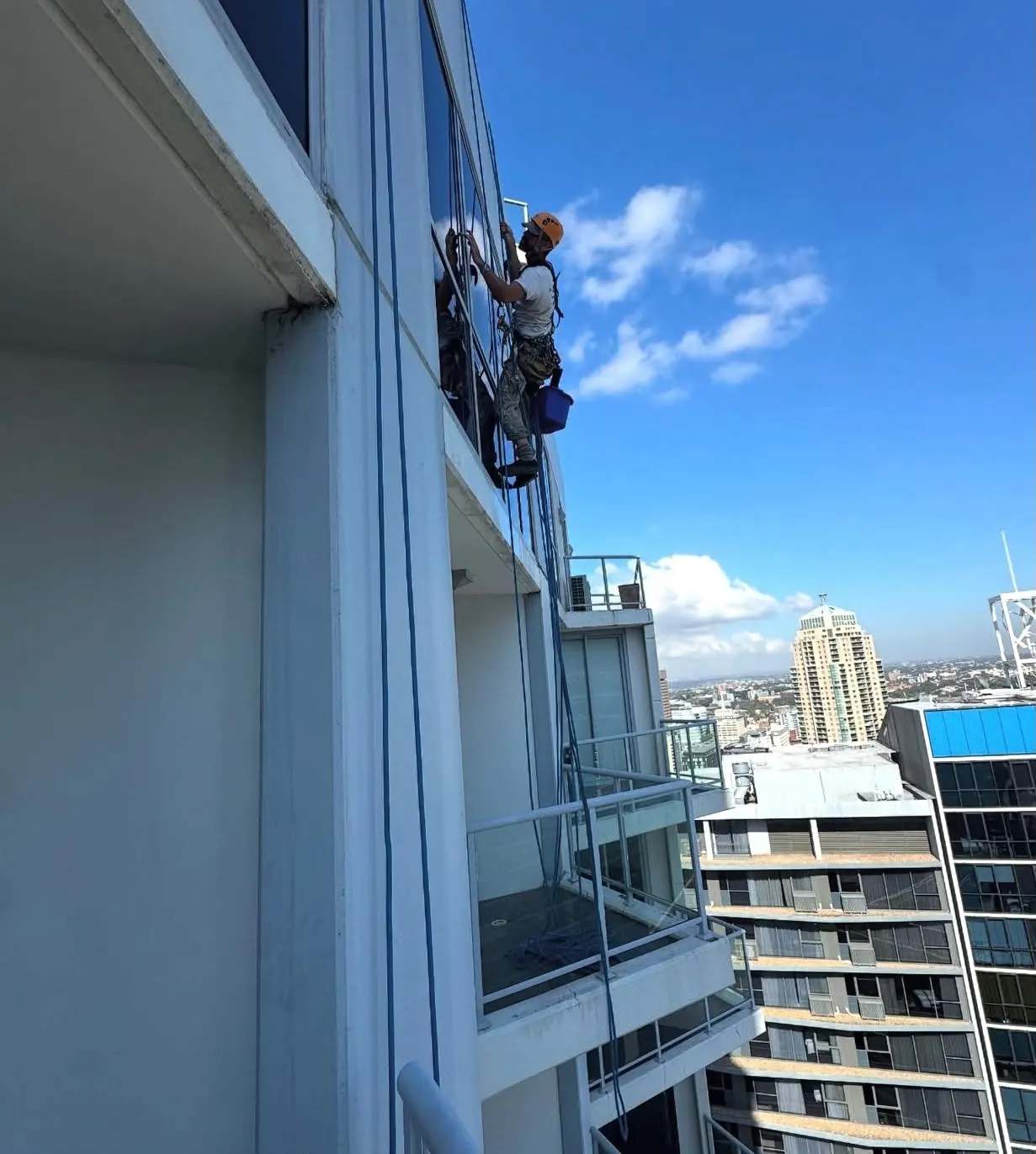 Window sealing on rope: technician caulking a window frame on a residential tower
